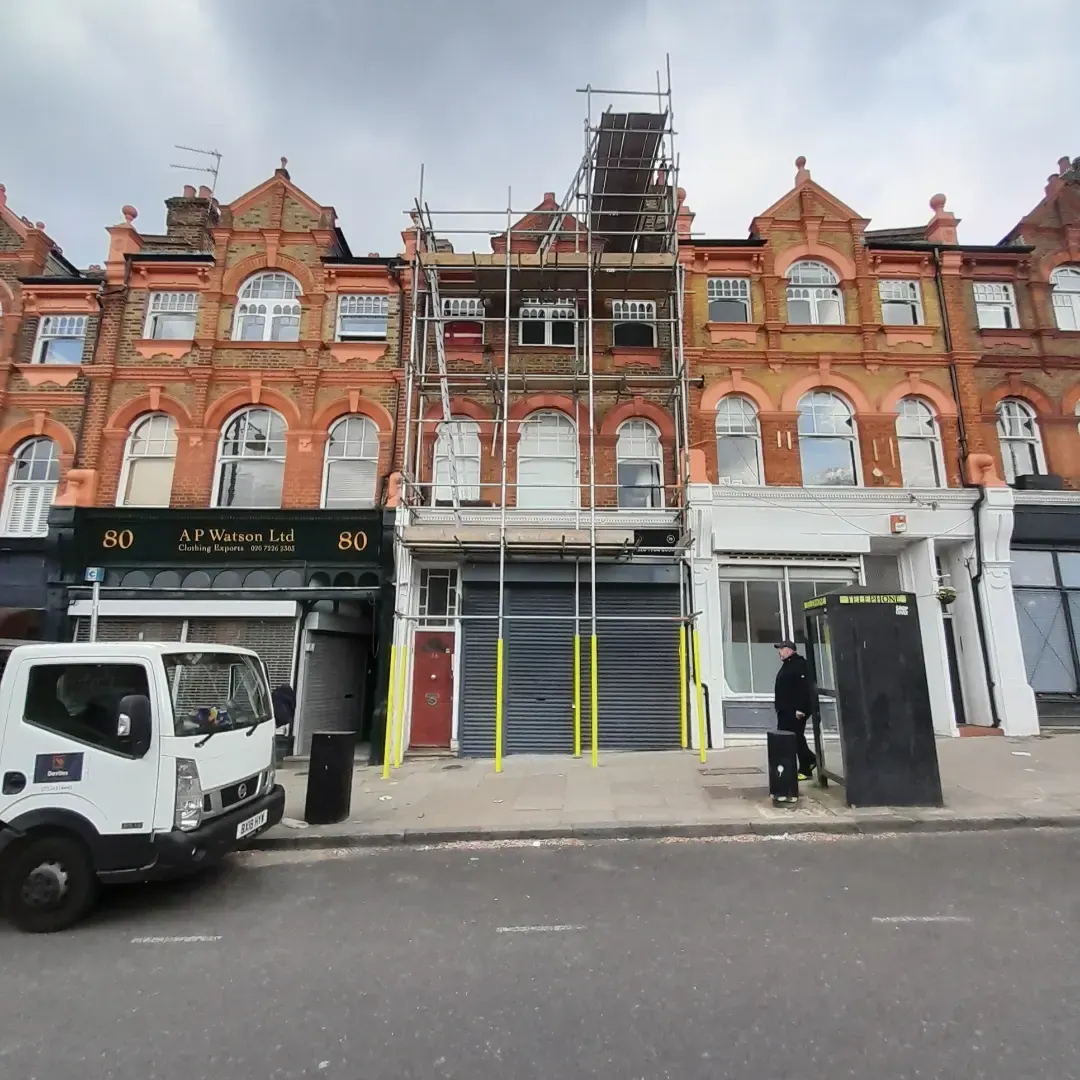 Devlins branded lorry beside a tall Edwardian scaffold on a North London shopfront