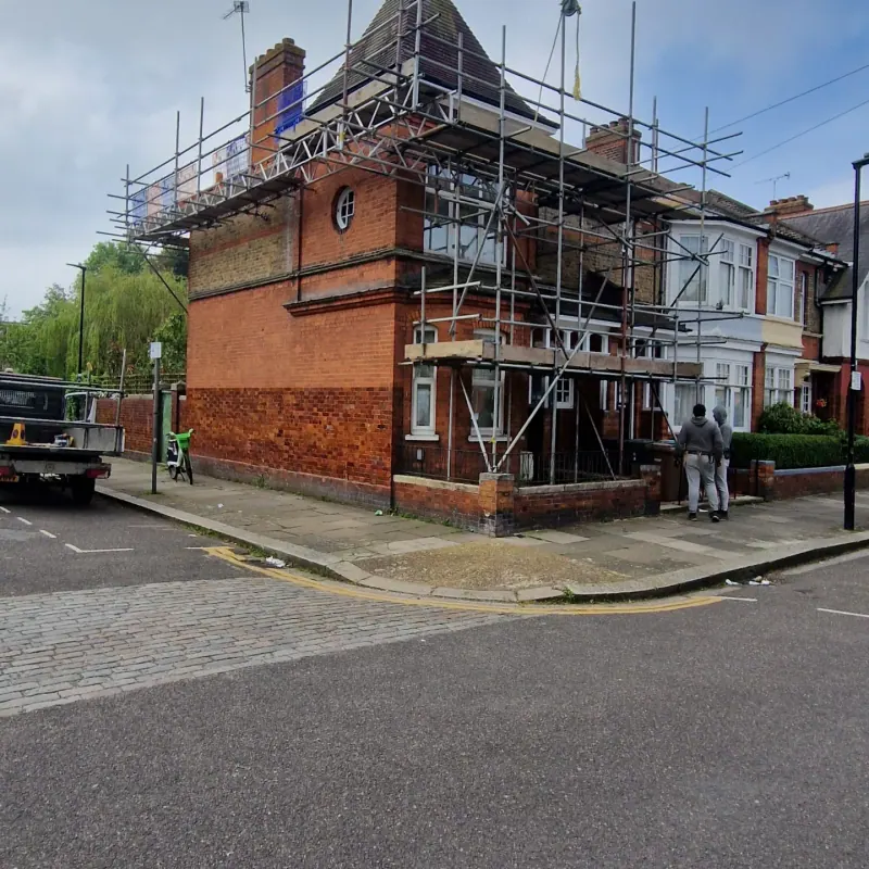Edwardian red-brick corner house scaffold with prominent chimney stacks