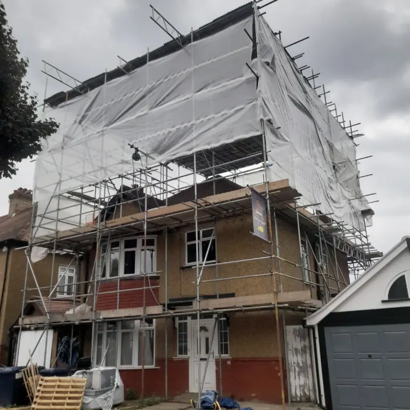 Semi-detached pebbledash house with full encapsulation scaffold and Devlins board