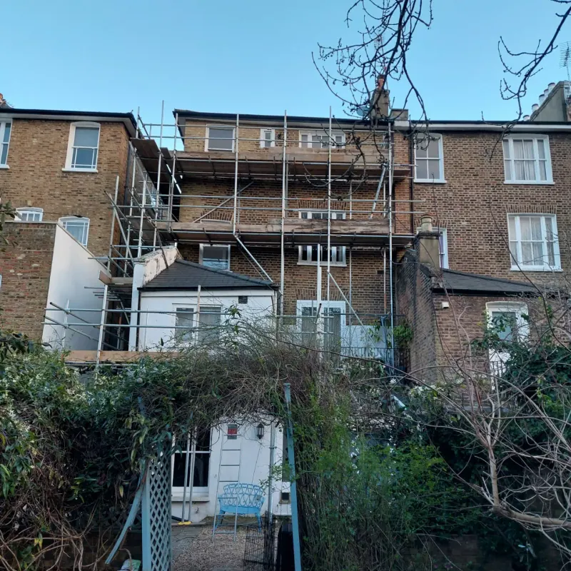 Victorian rear-garden scaffold bathed in golden-hour light
