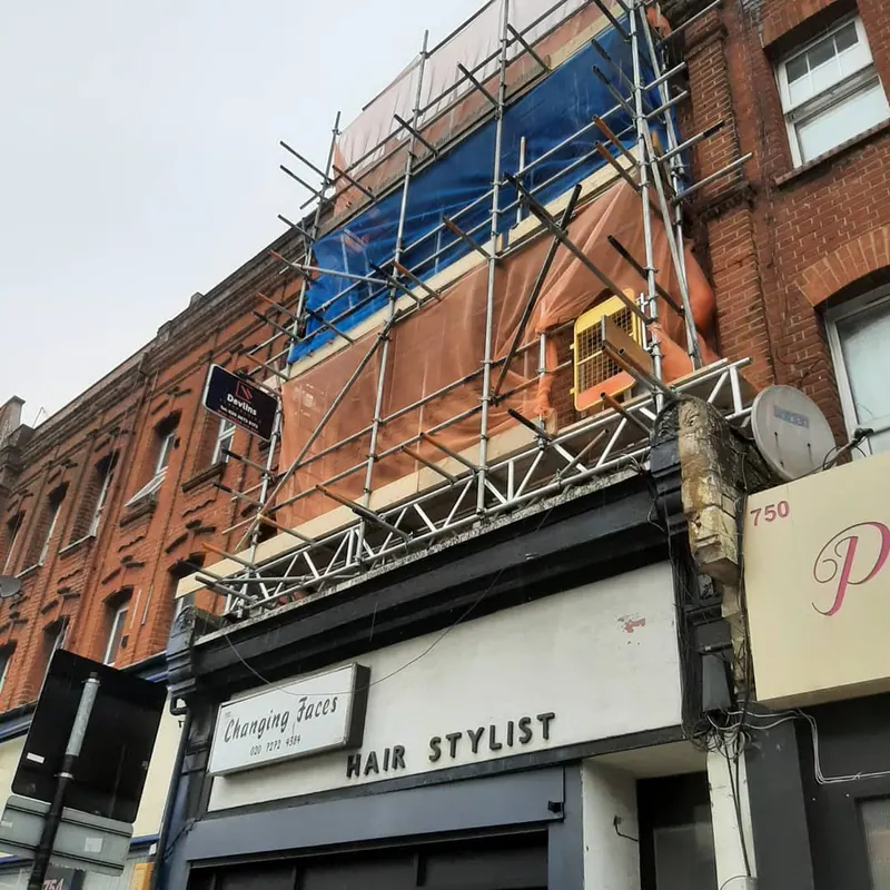 Commercial scaffolding on a redbrick shopfront in North London with Devlins board visible
