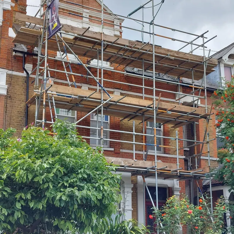 Residential scaffolding on a Victorian terrace with front garden foliage